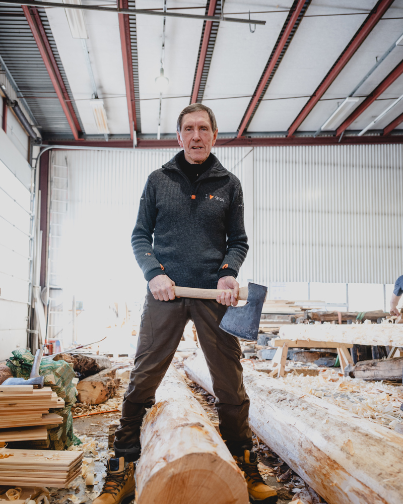 Foto av en mann som står over en tømmerstokk med øks.