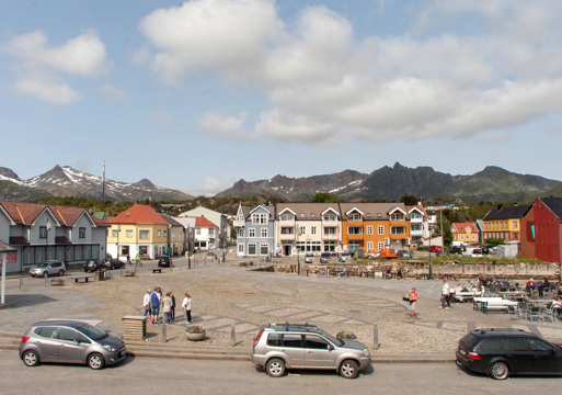 Foto av en tom plass i Kabelvåg med små trehus rundt