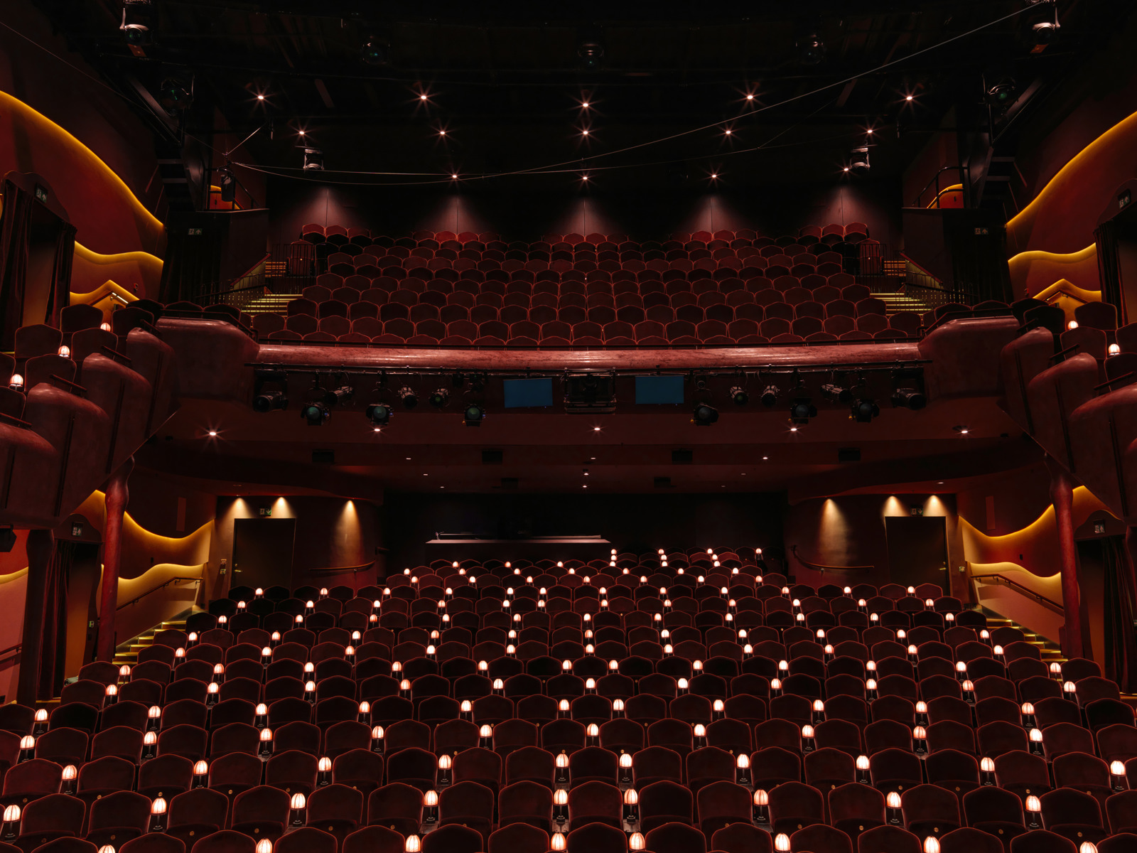 Interiørfoto av publikumssalen i Nye hjorten teater, små lamper ved stolene og to høyder med amfi.