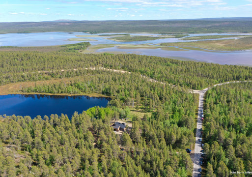 Fly/drone foto av skog, hytte i skog, vei i skog og ulike vann. 