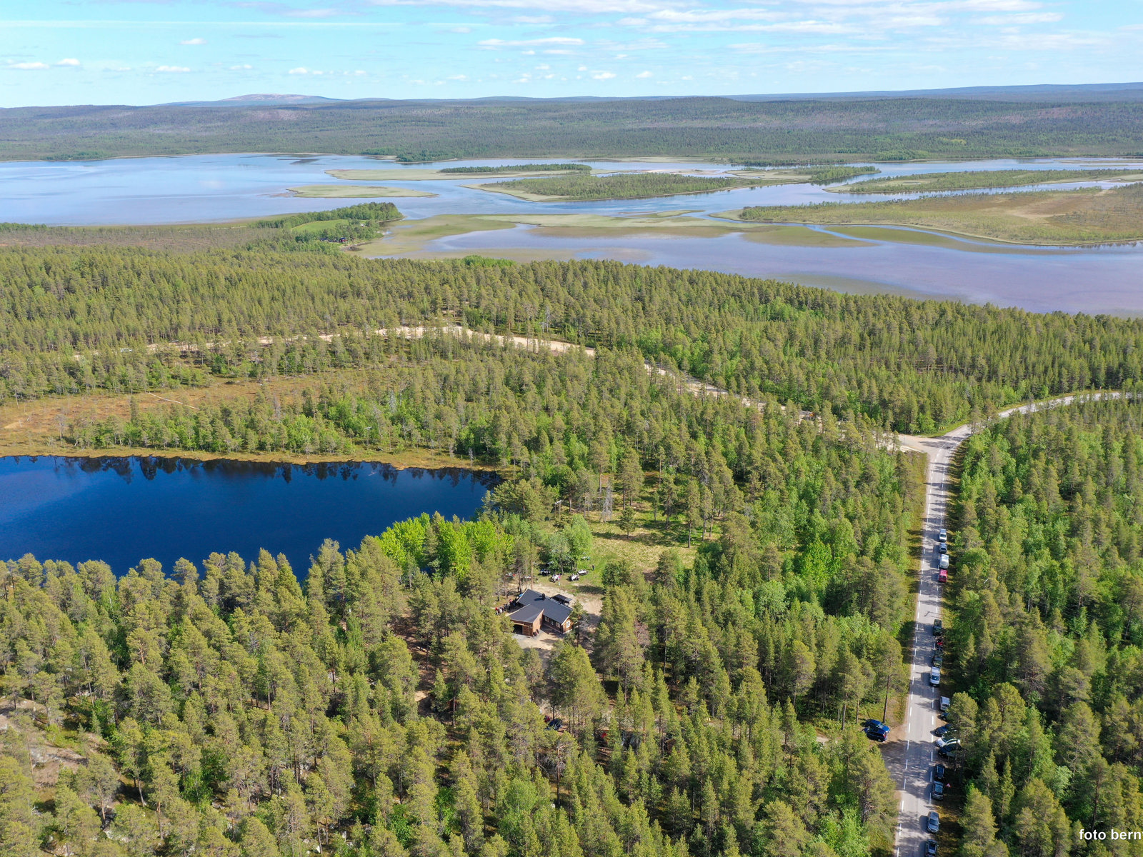 Fly/drone foto av skog, hytte i skog, vei i skog og ulike vann.