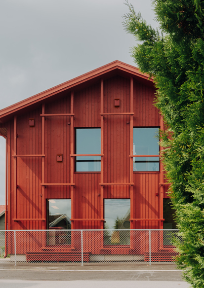 Fasade foto av Alvim barnehage, rød gavl vegg, tre og vei med en bil som kjører fremfor.