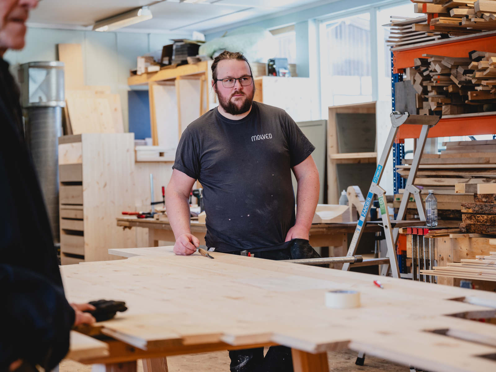 Foto av en mann som står på et verksted og tegner på en treplate.