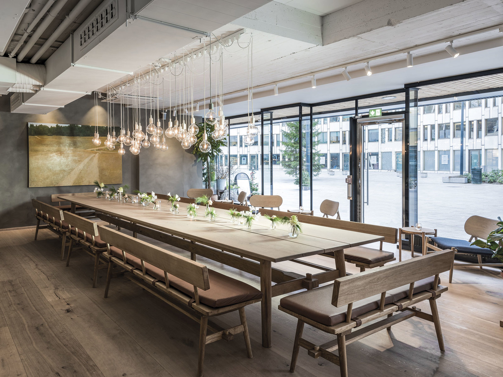 Interiørfoto av restaurant med langbord og mindre sittegrupper. 