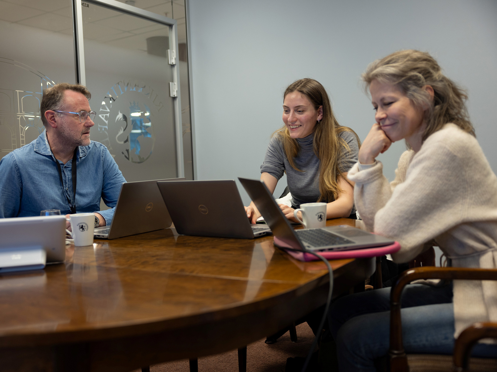 Foto av tre mennesker som sitter rundt et bord og jobber på PC'er.