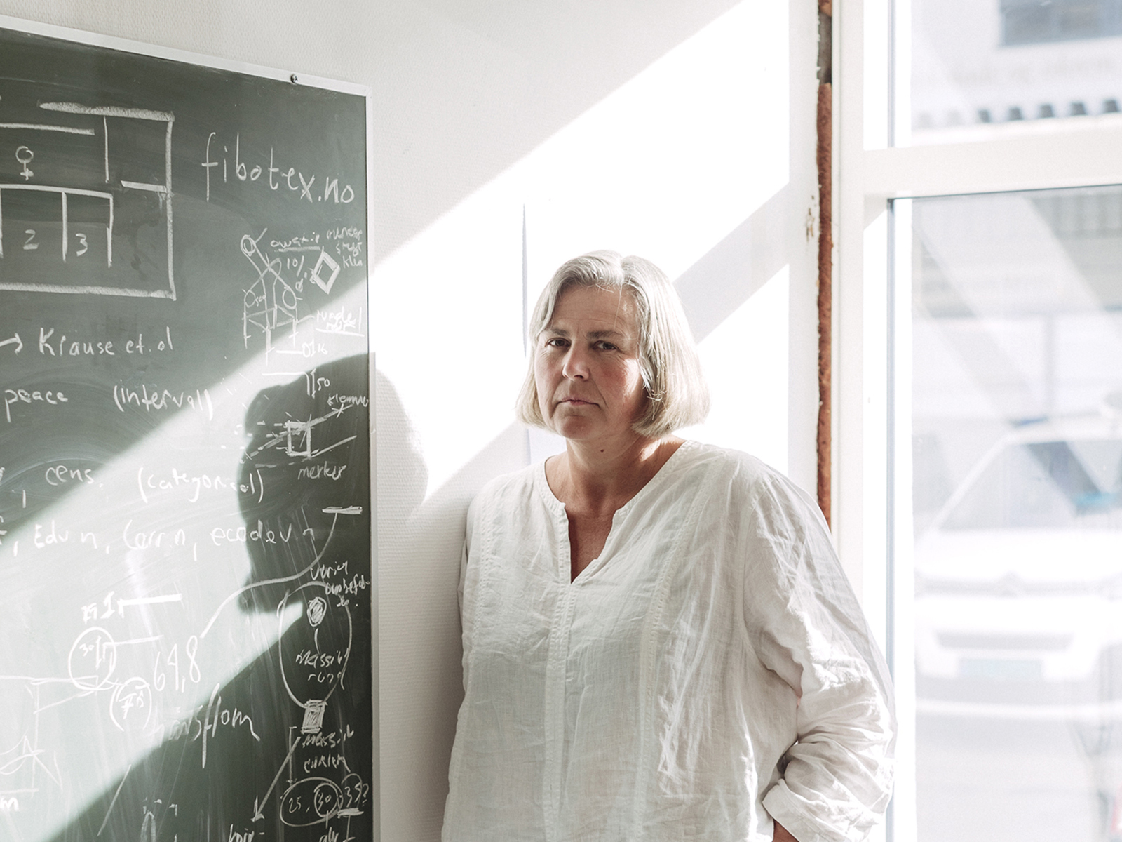 Portrett av Beate ved siden av en grønn tavle og dagslys gjennom vinduet bak henne.
