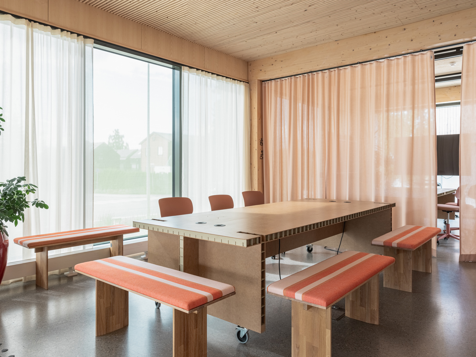 Interiørfoto av møterom, krakker med oransje og hvit stripede puter.