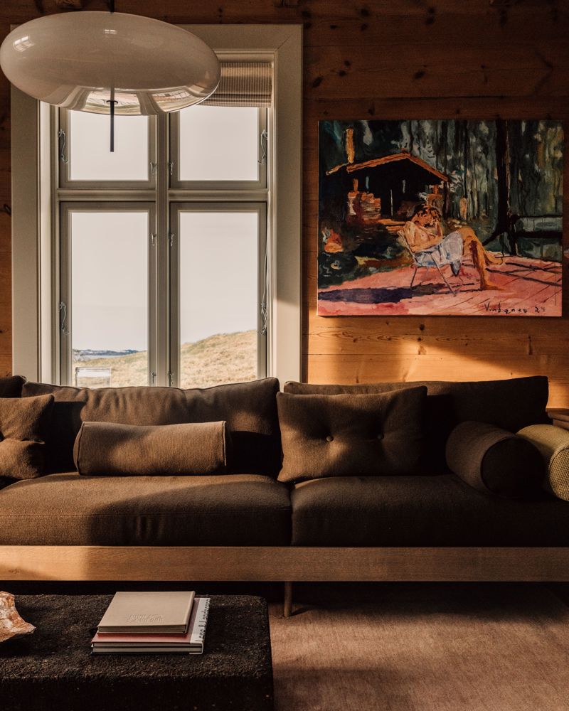 Interiør foto av en stue, brun sofa, maleri og utsikt til naturen.