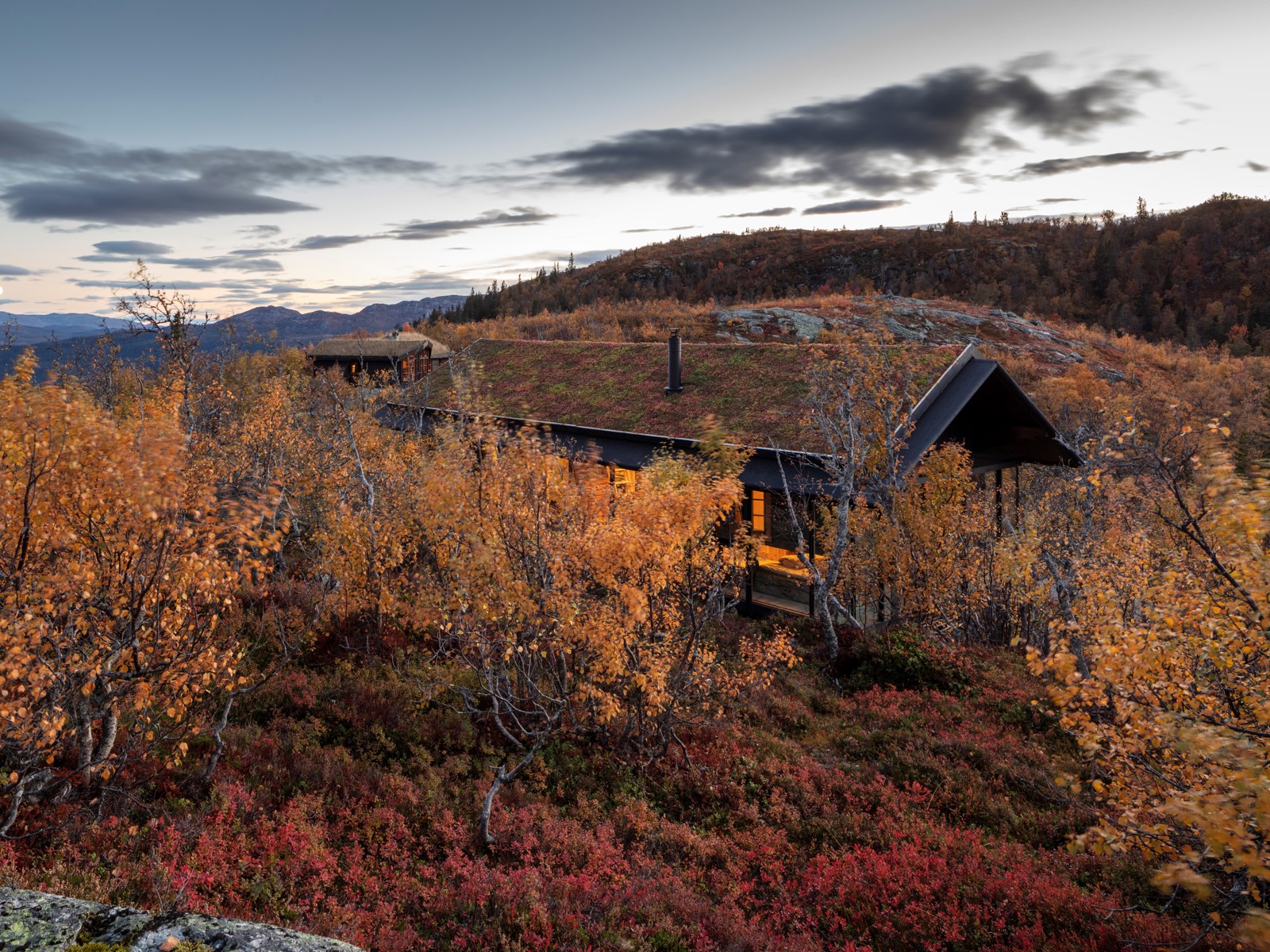 Foto av hytte i høstlandskap.