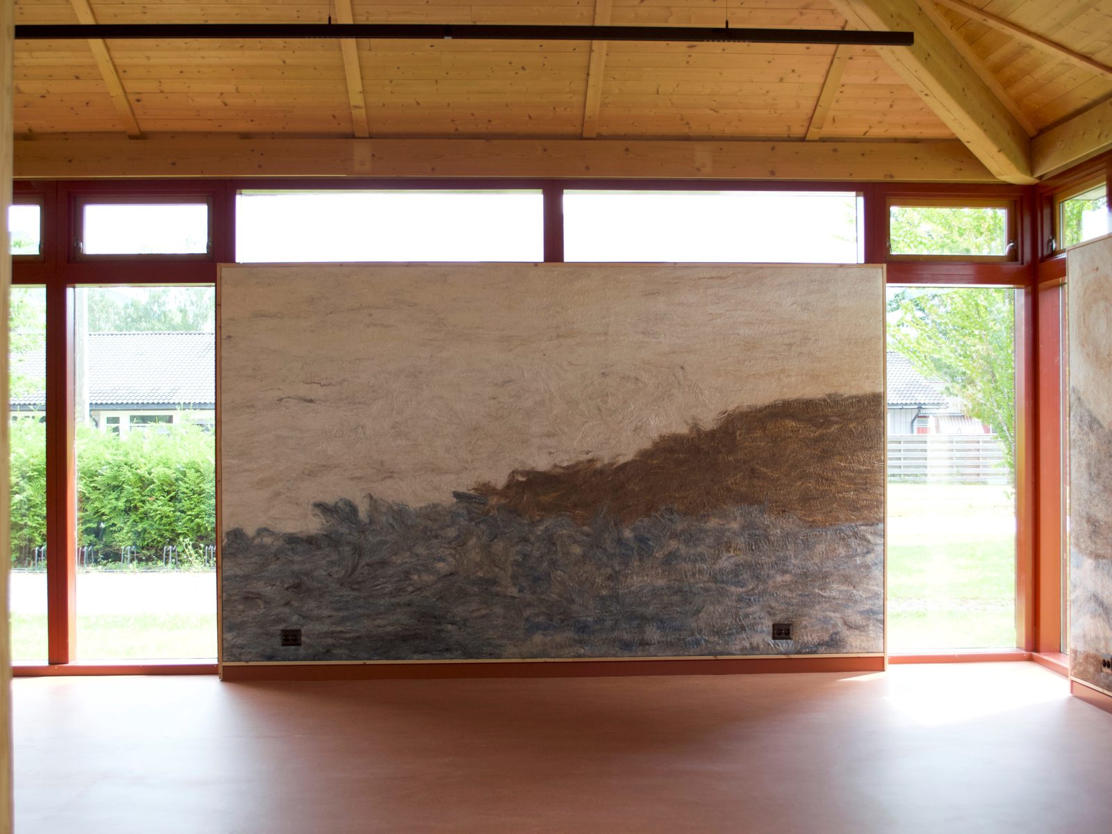 Interiør foto av rom med en vegg av tovet ull midt i, vinduer rundt.