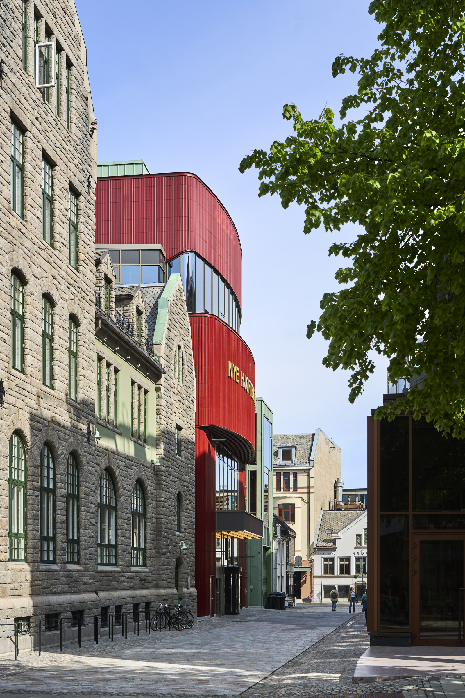 Foto nedover gate, bygningsrekke på venstre side med Nye Hjortens røde fasade som skiller seg ut.
