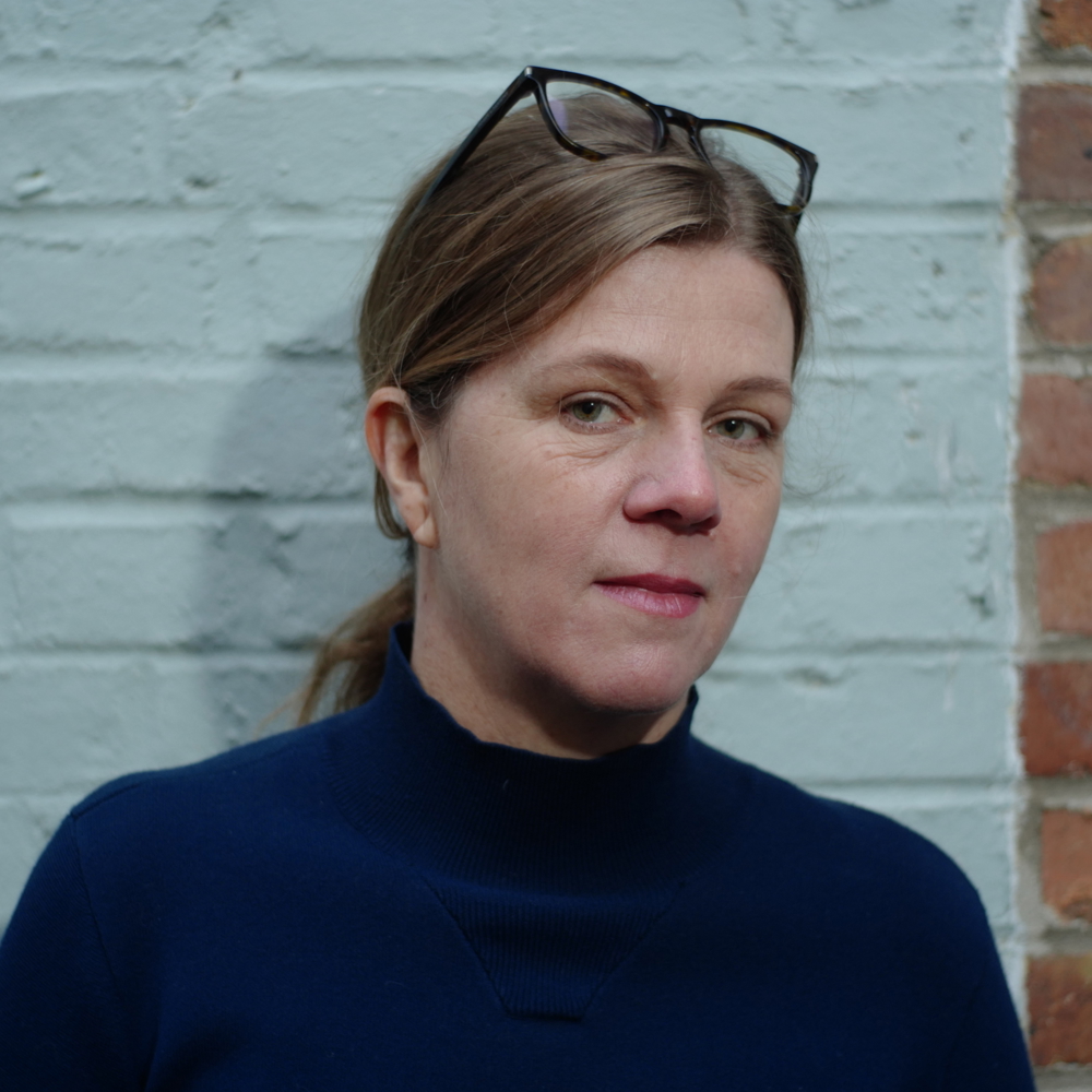 Portrettbilde av Emma Nilsson inntil en murvegg. Foto.