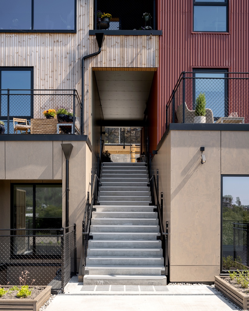 Foto av inngangsparti til boligkompleks, trapp opp og tre fasade i ulike farger. 