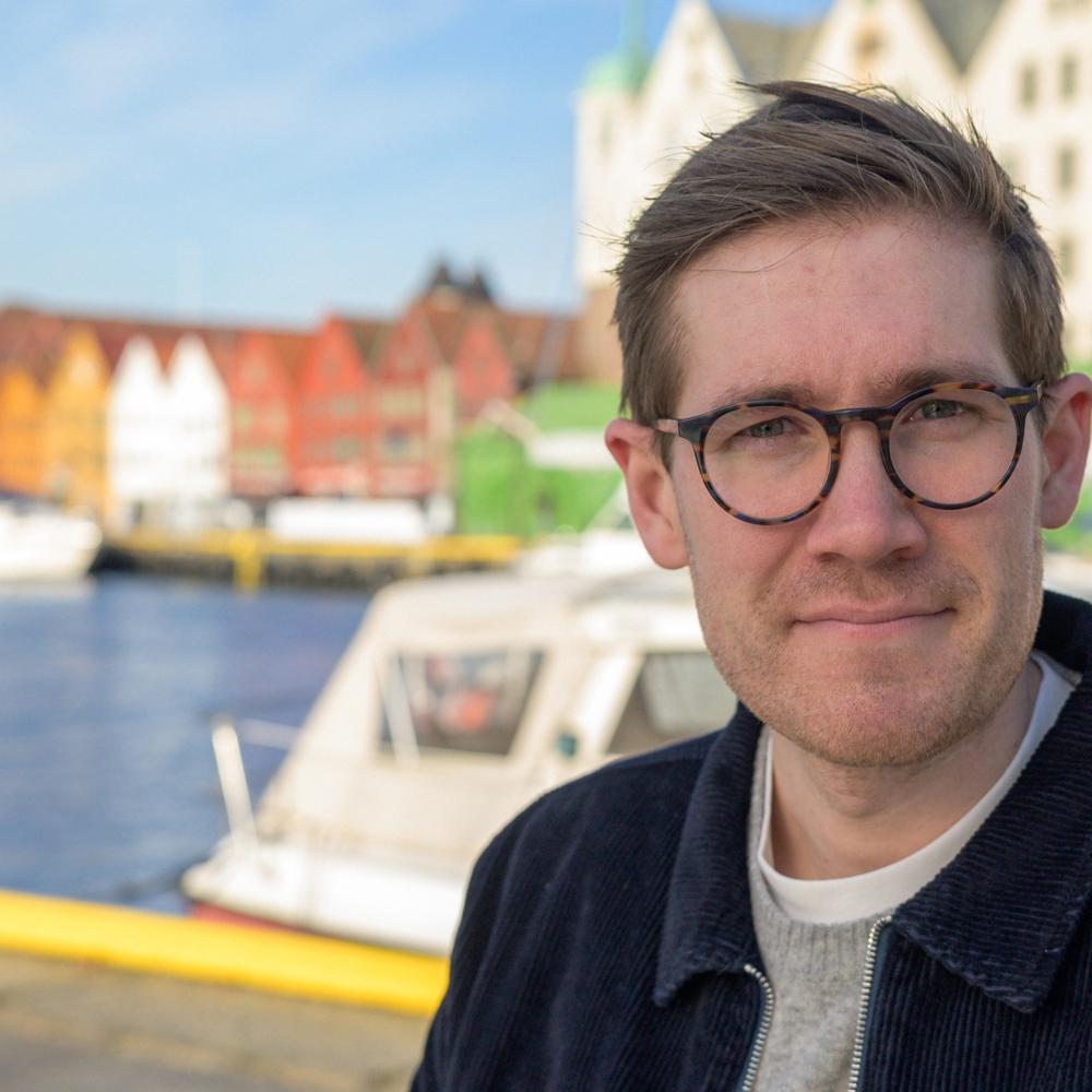 Portrettbilde av Thor Haakon Bakke med Bergen brygge i bakgrunnen. Foto.