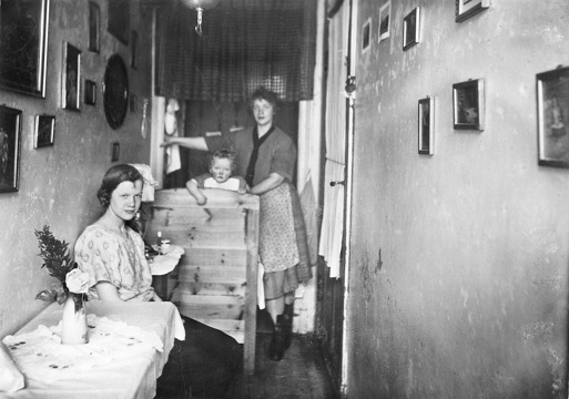 Svar/hvitt foto fra arkivet av to kvinner og et barn i en trang gang, fra 1800-tallet.