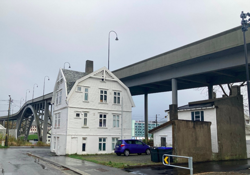 Bilde av et hvitt hus delvis under en bro. Foto.