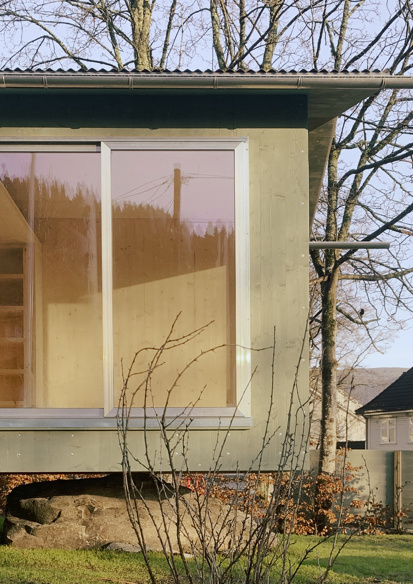Eksteriørfoto av skuret som viser hvordan bygningen hviler på en stor sten, samt den grønne kledningen 
