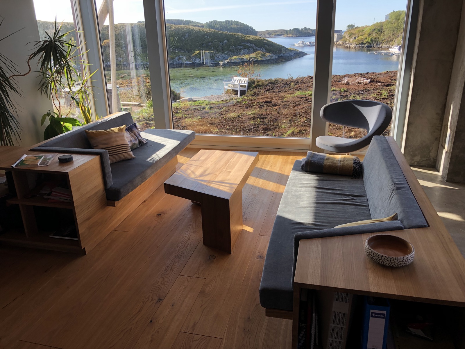 Foto av stue med tilpassede møbler i treverk, utsikt til natur.