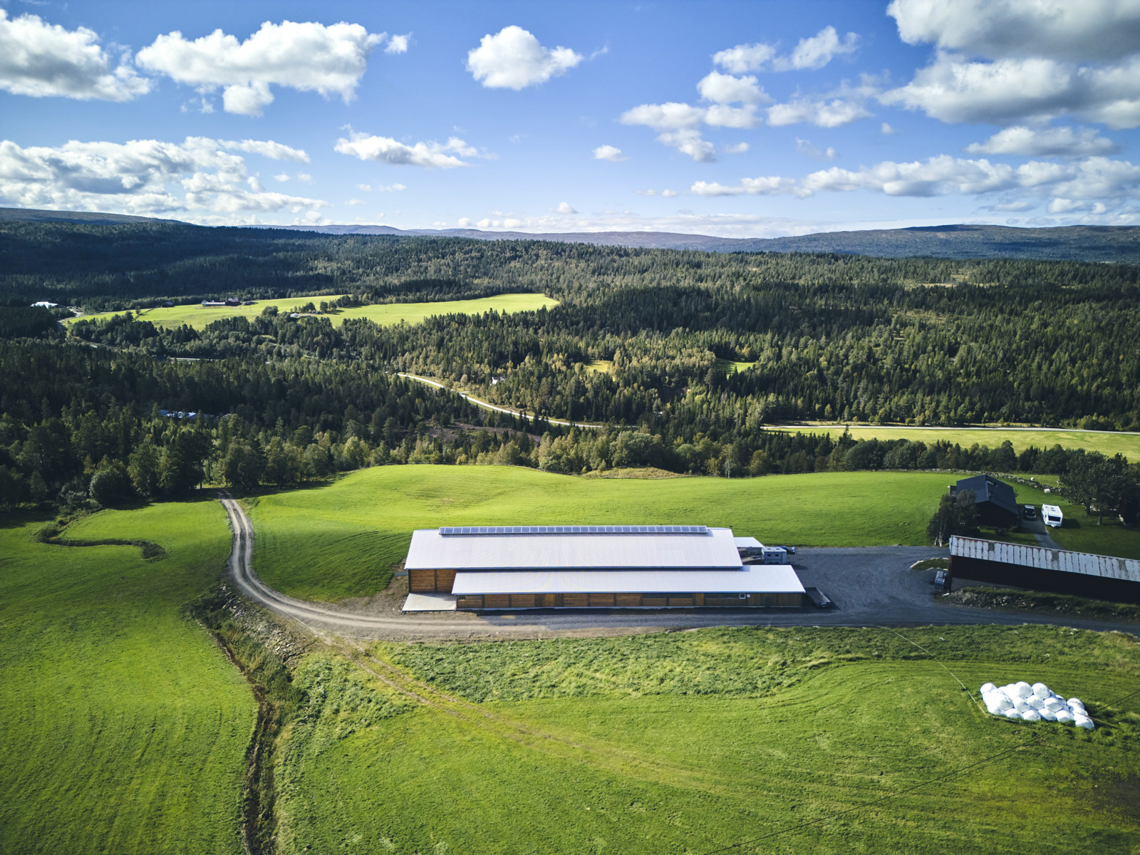 Flyfoto som viser plasseringen av fjøs i et grønt landskap. 