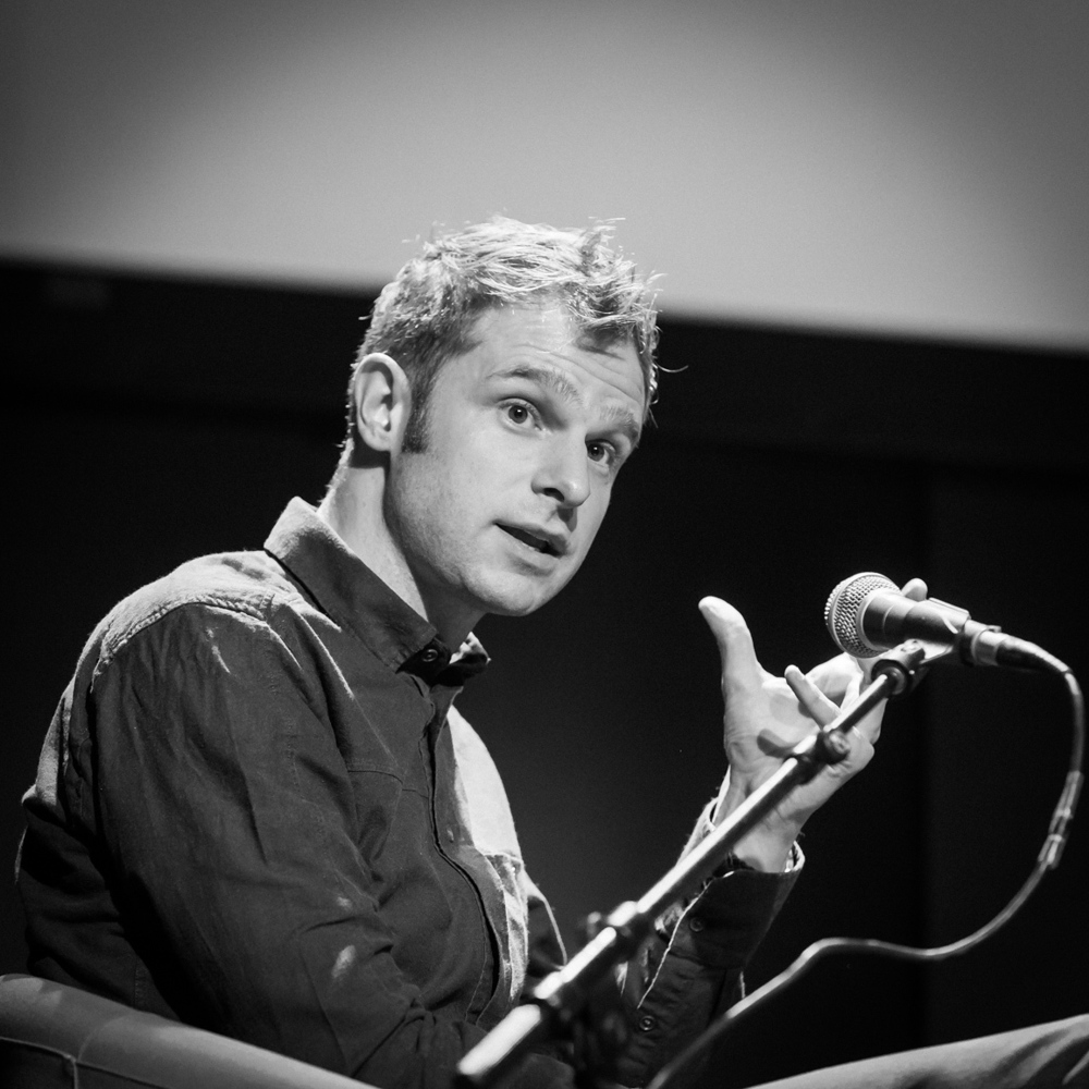 Snorre Valen snakker i en mikrofon, svart hvit. Foto.