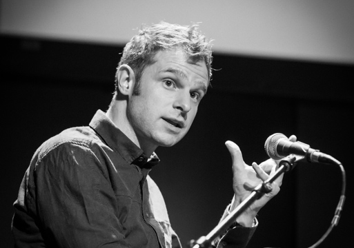 Snorre Valen snakker i en mikrofon, svart hvit. Foto.