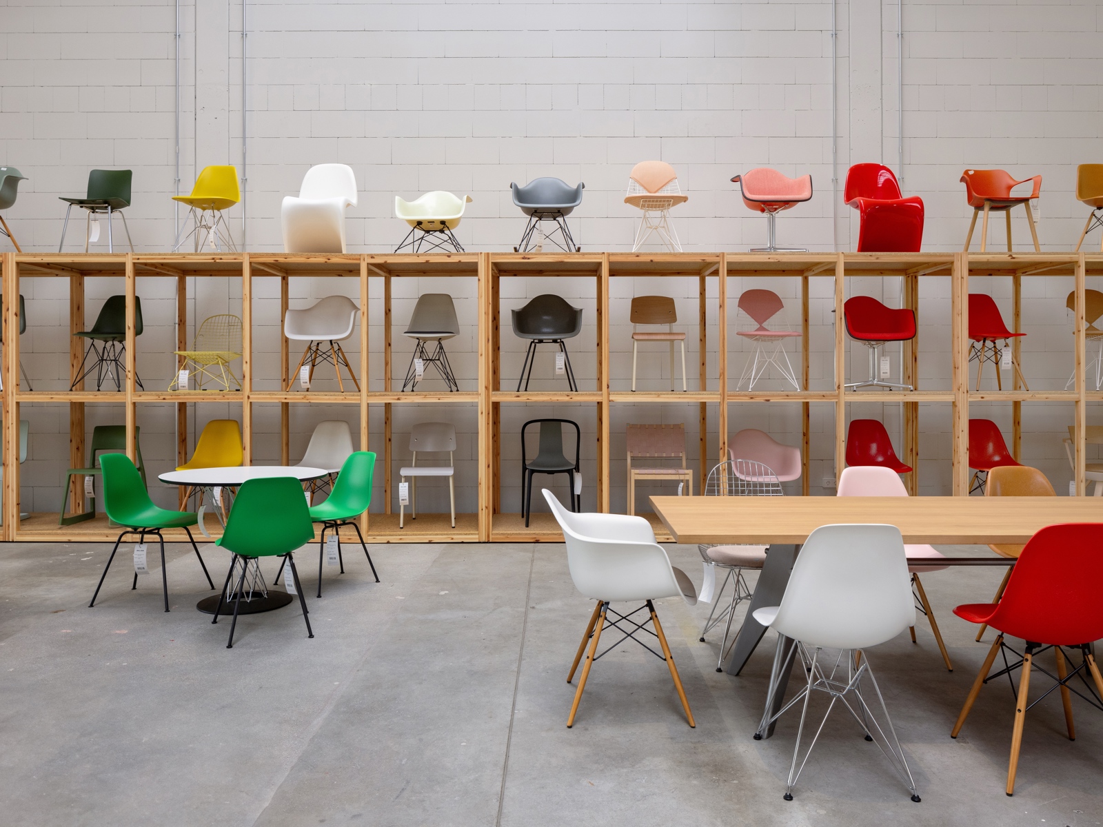 Interiør foto av et stort rom med stoler stilt opp i en hylle langs veggen og sittegrupper på gulvet.