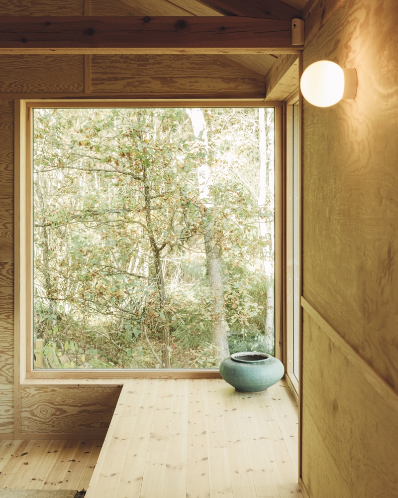 Interiør foto, treverk, lang benk og vindu med utsikt til skog. 
