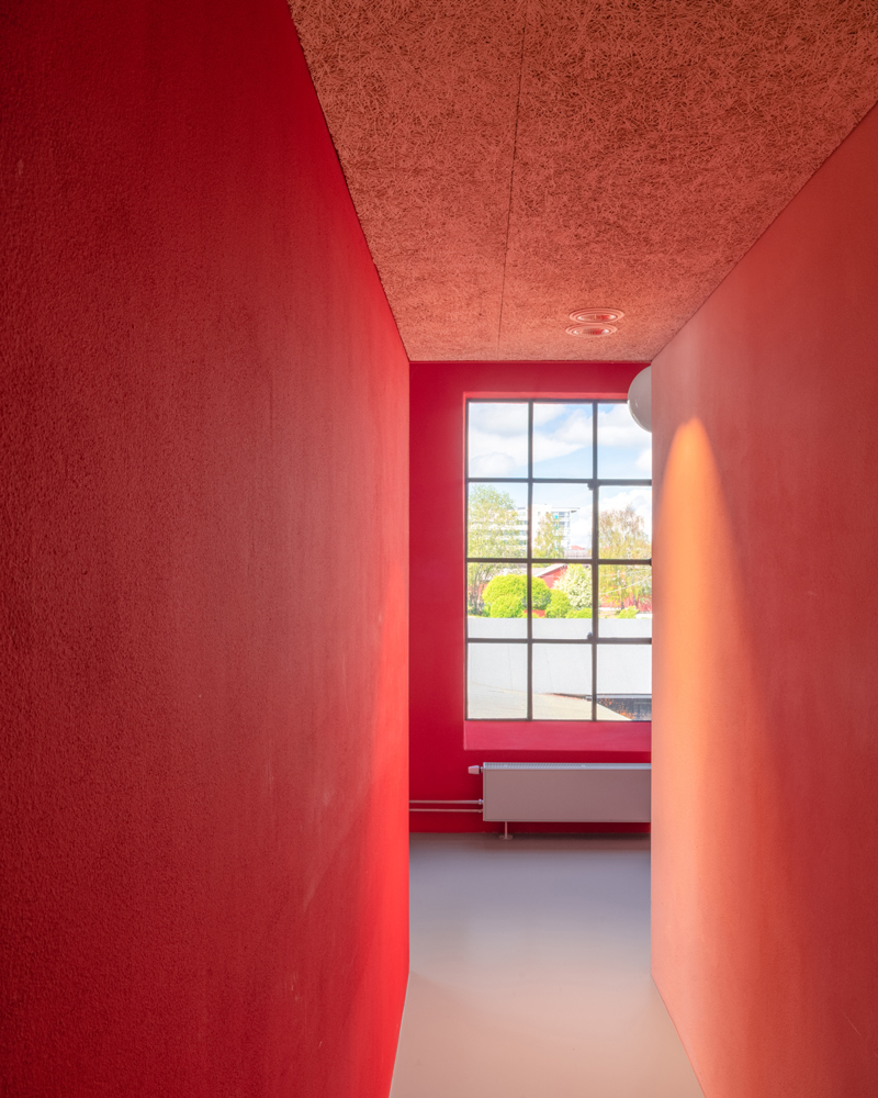 Interiør, rød gang med vindu i enden. Foto.
