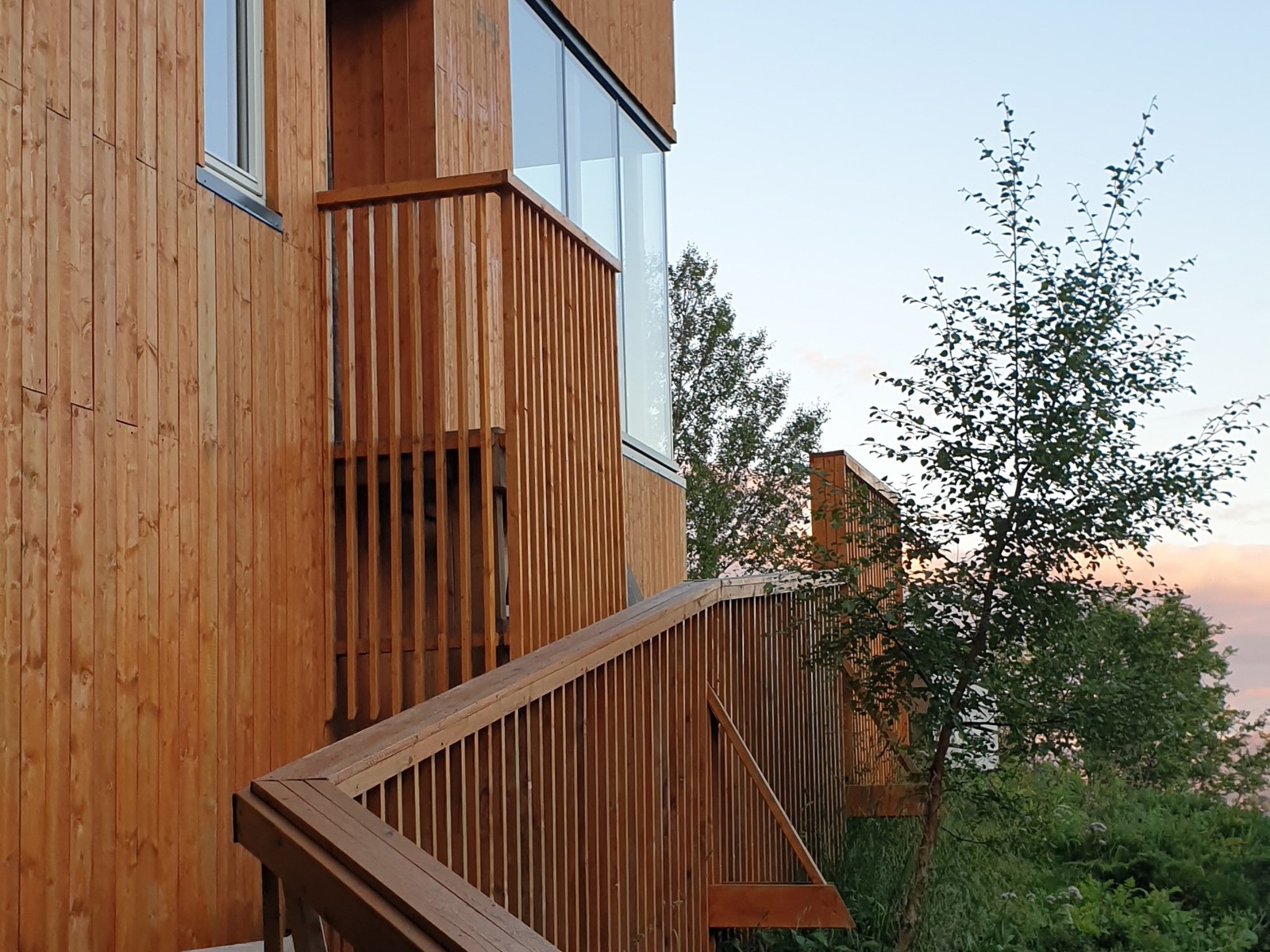 Foto av inngang til saunahus i treverk i en grønn hage.