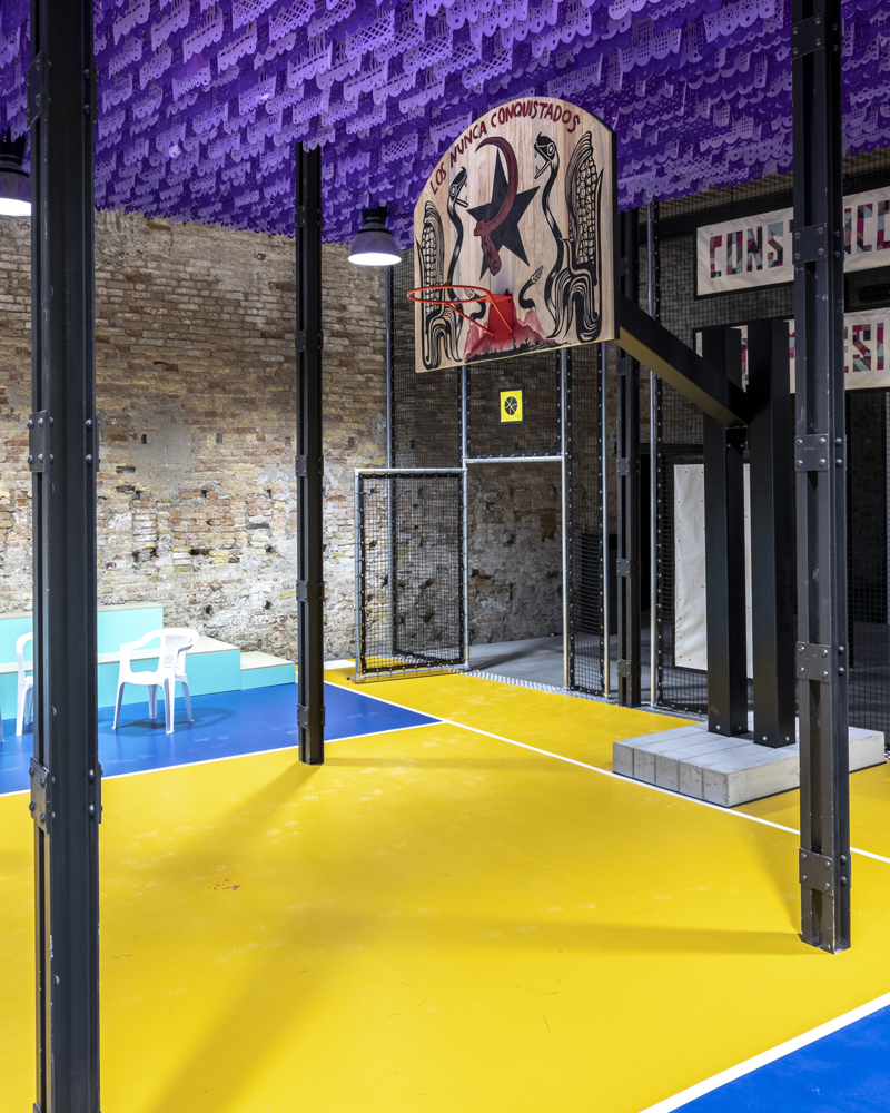 Foto av innendørs basketball kurv, gult gulv og lilla tak. 