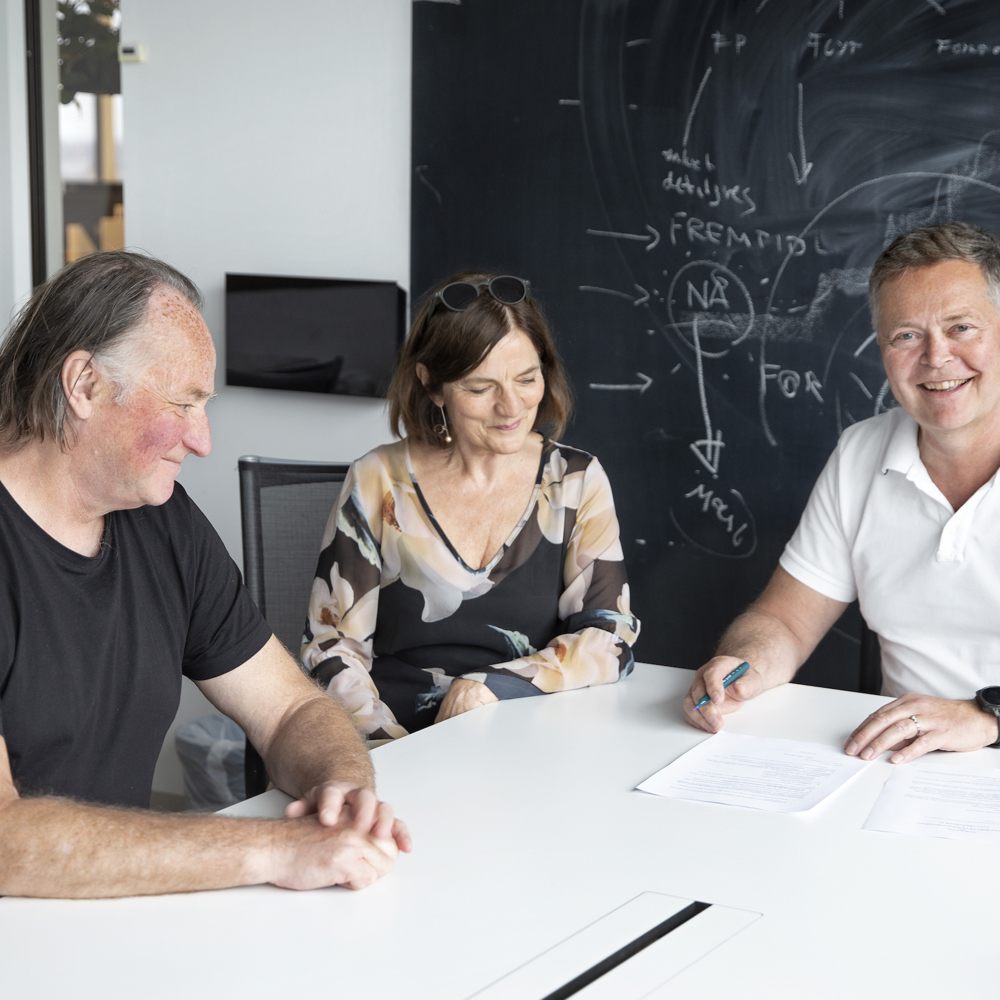 3 mennesker signerer en kontrakt. Foto.