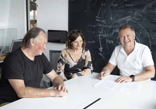 3 mennesker signerer en kontrakt. Foto.