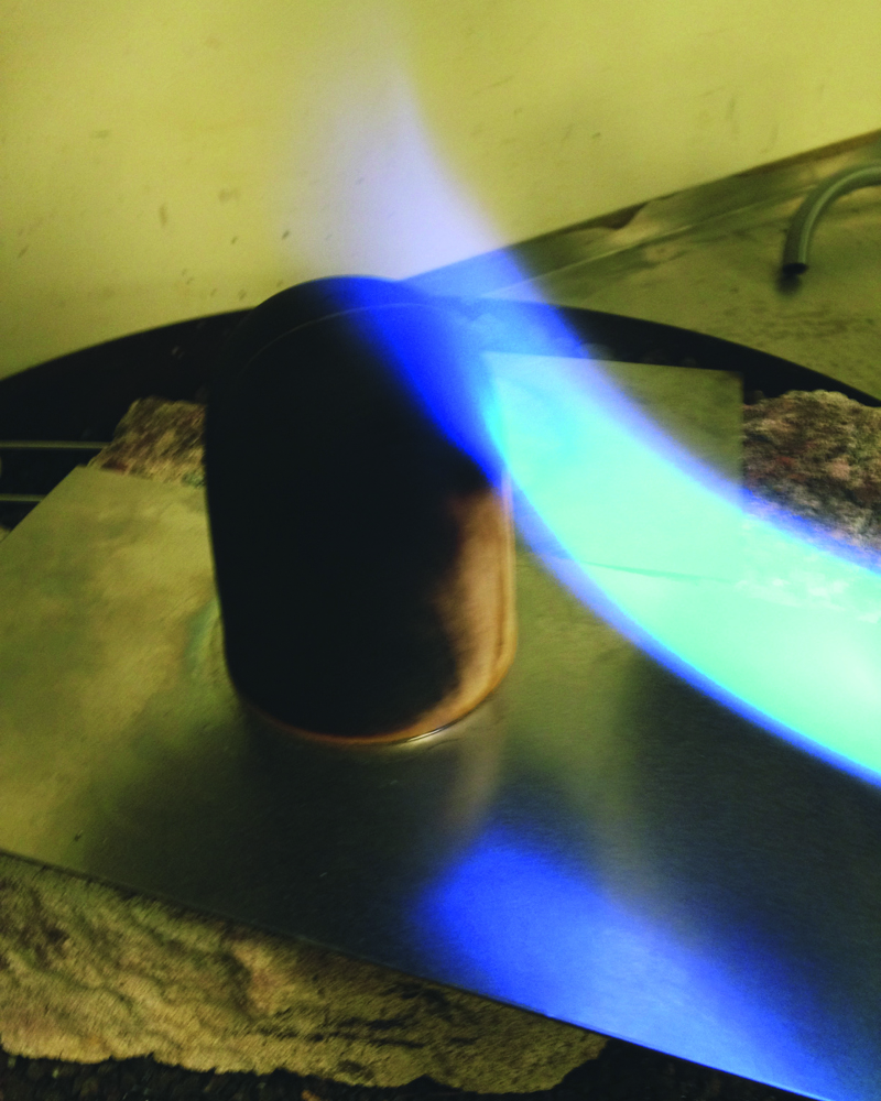 Flamme på et stykke treverk. Foto.