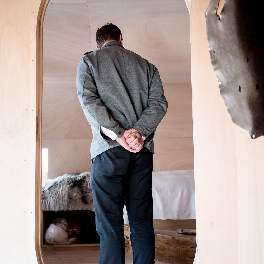 Espen Folgerø med ryggen til i en oval døråpning av tre. Foto.