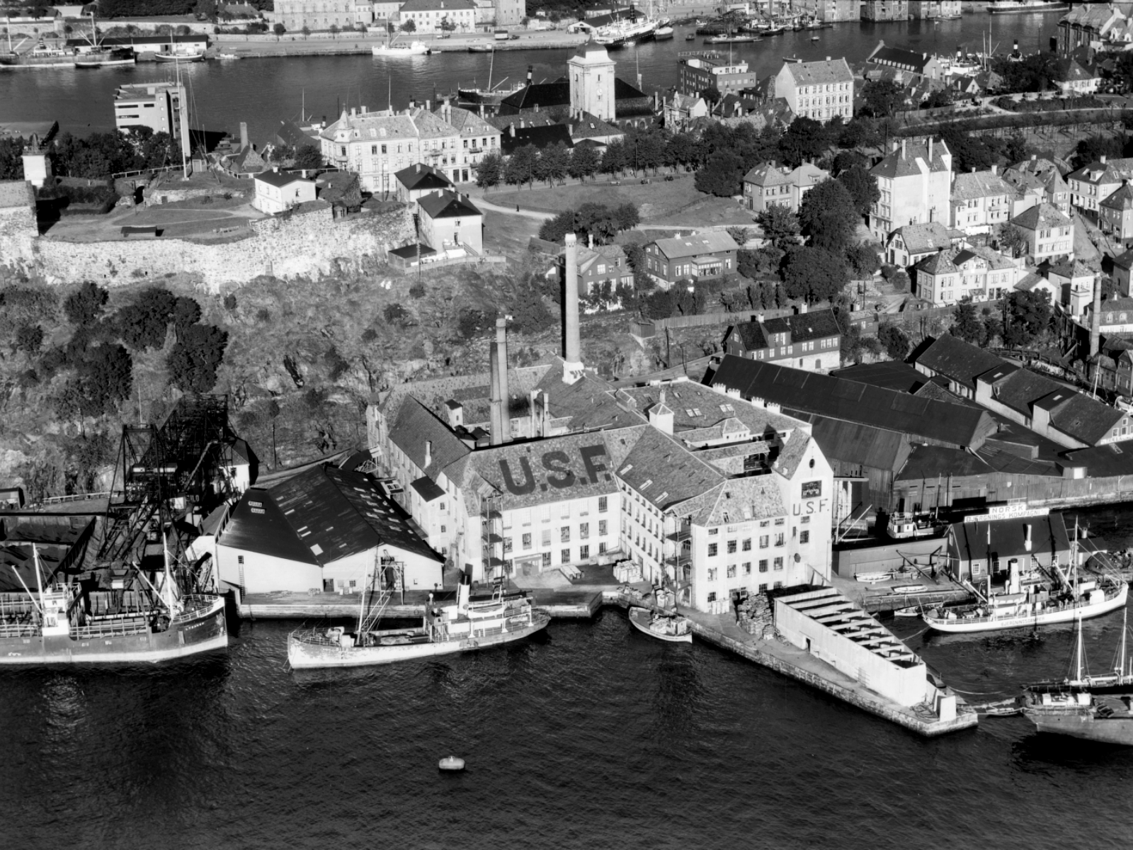 Svart hvitt oversiktsbilde av havneområde. Foto.