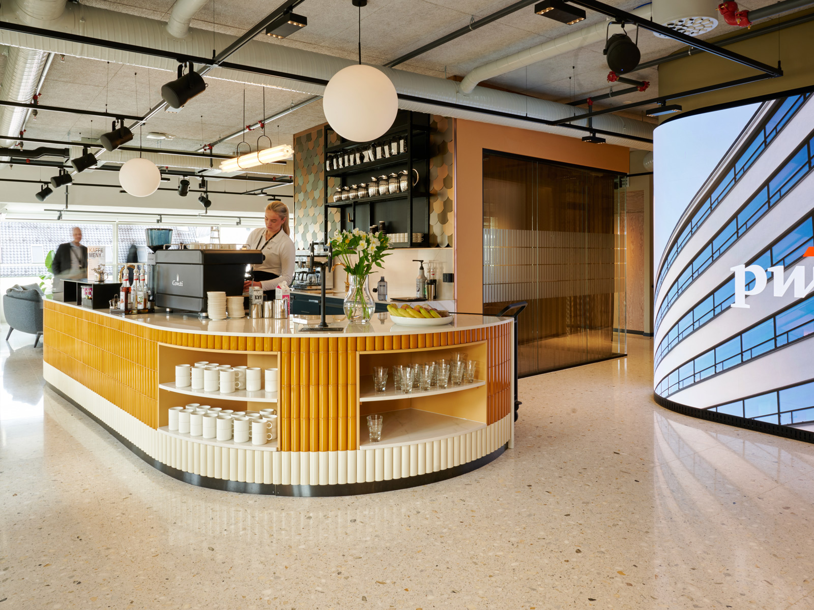 Interiørfoto av en rund kaffebar kledd i gule og hvite fliser i Sundt-bygget