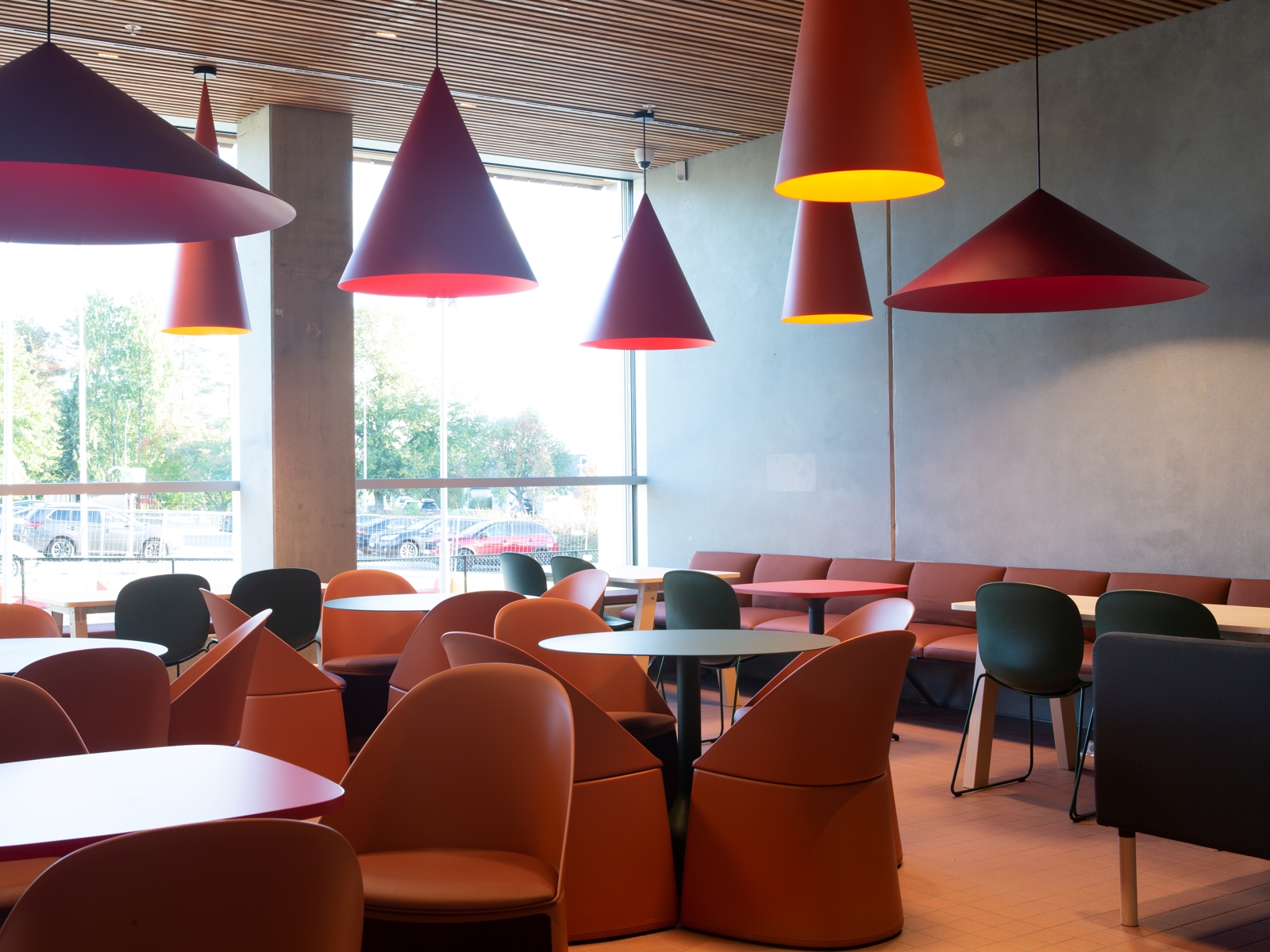 Interiør foto av kafé med mange sittegrupper, rødt interiør detaljer.