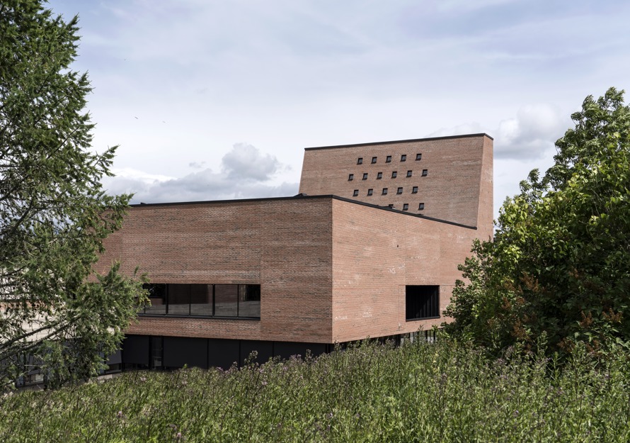 Spikkestad kirke avbildet utenfra, med grønn eng i forgrunnen og trær på sidene.