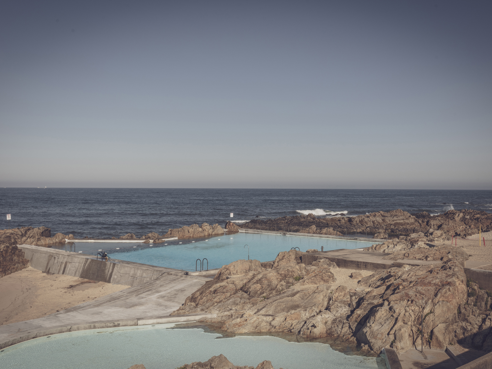 Badebasseng i et stein-landskap med utsikt til havet. Foto.