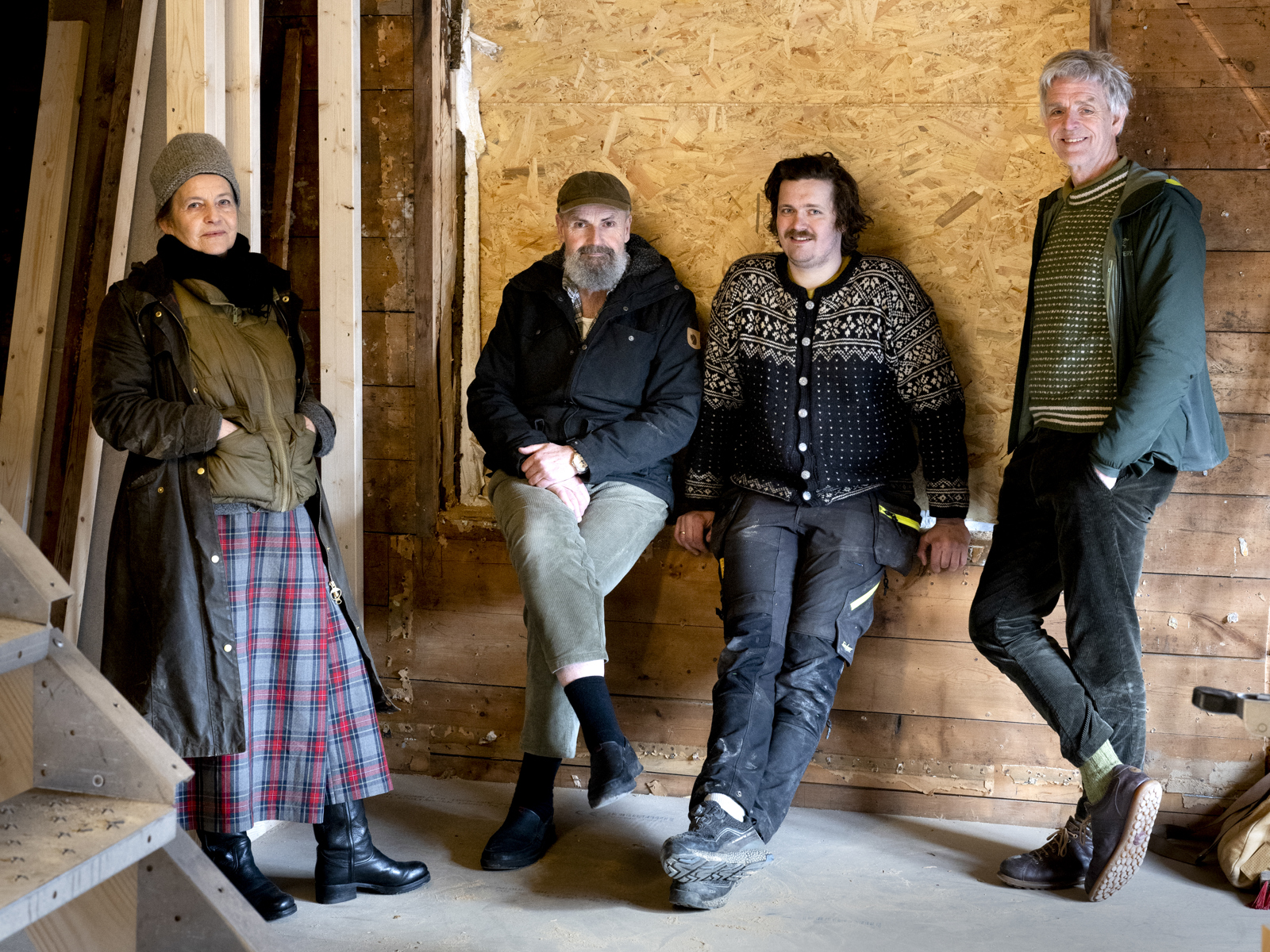 Foto av en gruppe mennesker som lener seg inntil en vegg i et oppussingshus.