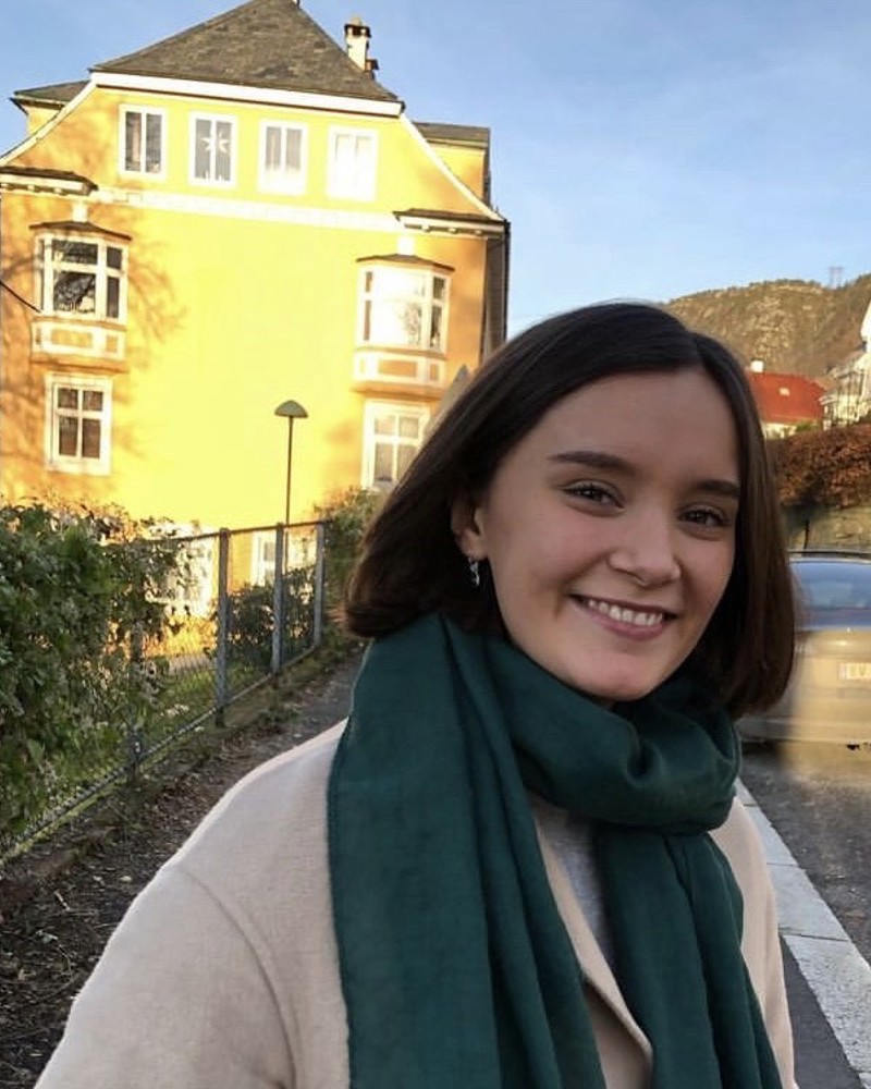 Portrett av Jill-Andrea Simonsen foran et gult hus.