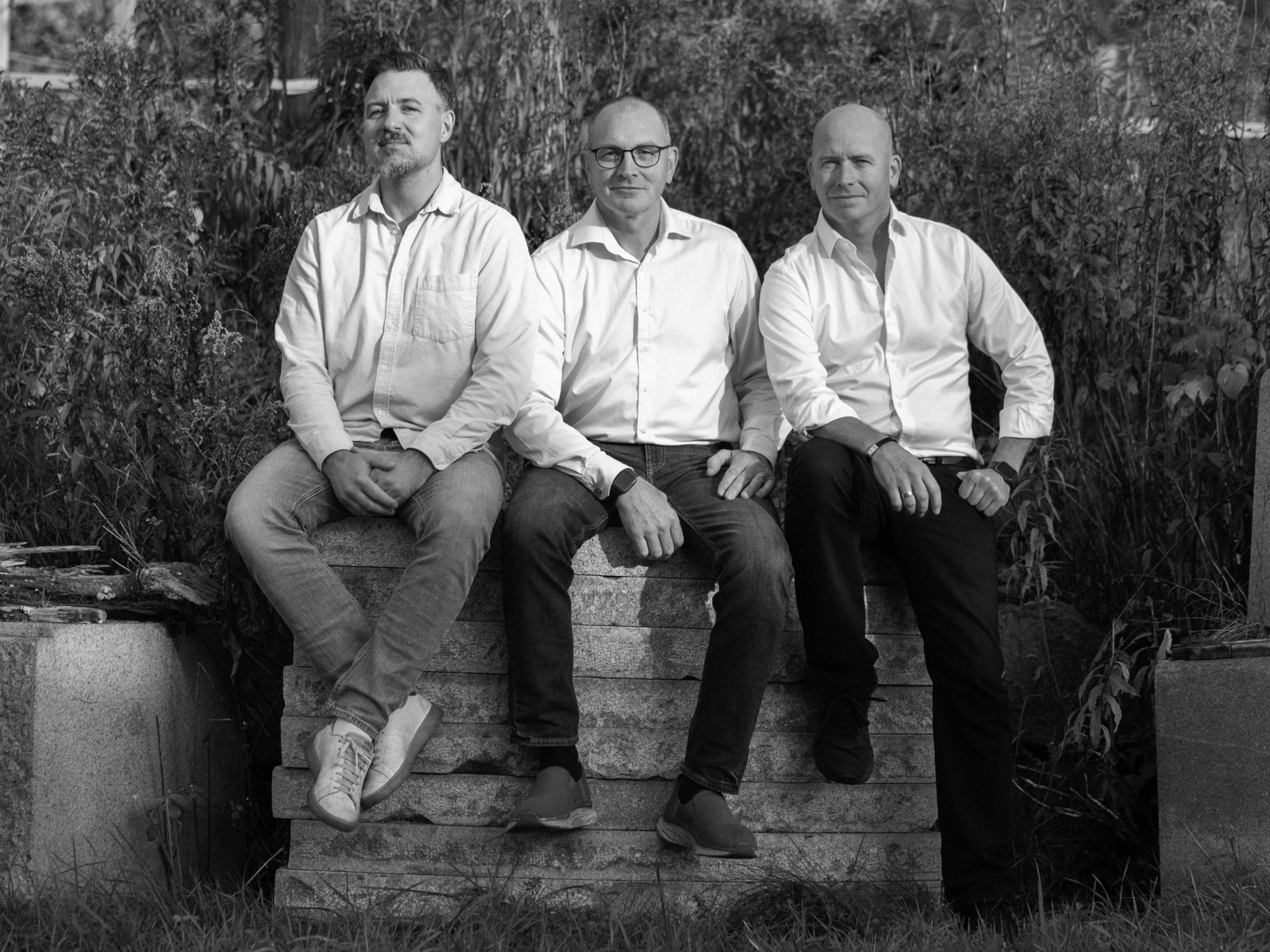 Foto av tre menn i skjorte som sitter på steinheller. 