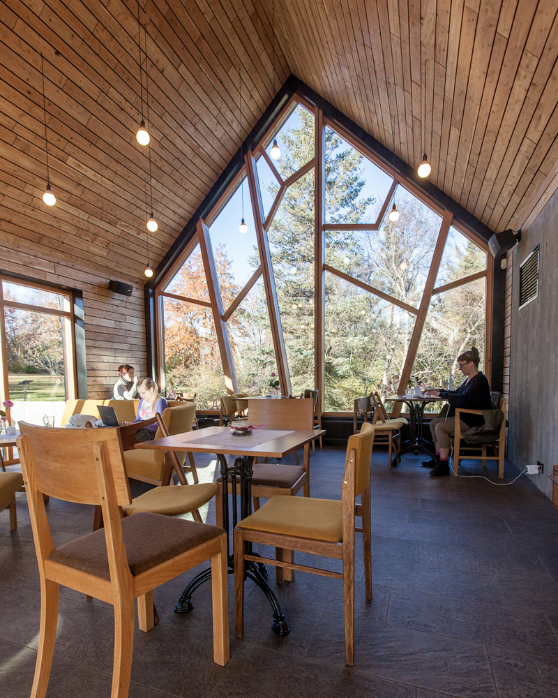 Interiør foto av en kafé, ulike sittegrupper og stort vindu i gavlvegg.