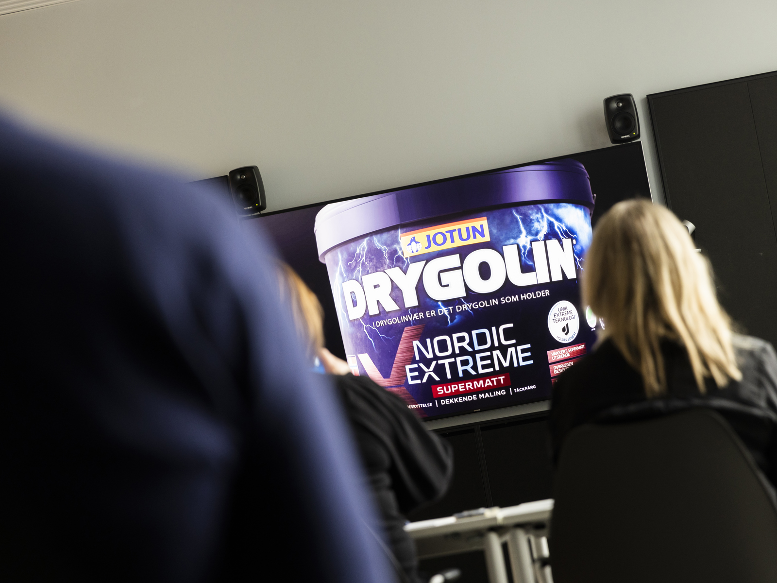 Reklame for maling på en tv-skjerm, mennesker som ser på tv-en. Foto.