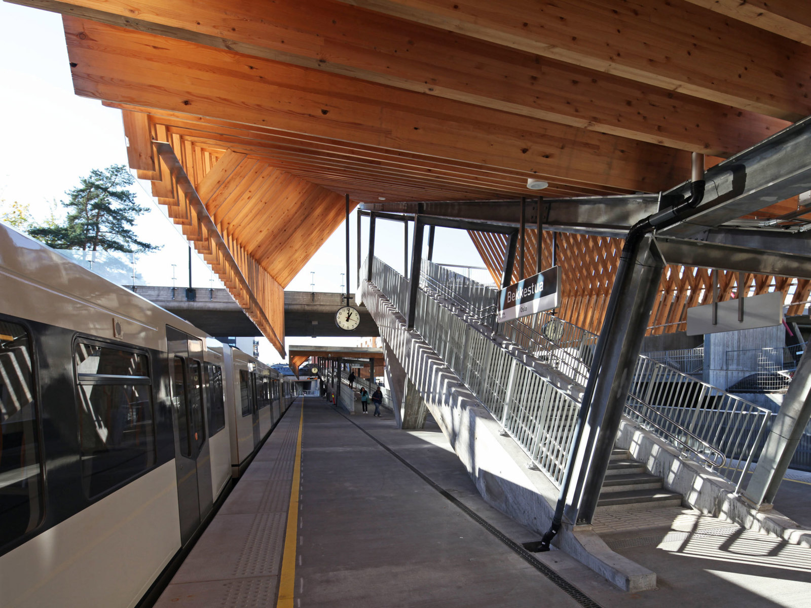 Foto av plattform på Bekkestua stasjon, trekonstruksjon over, tog parkert.