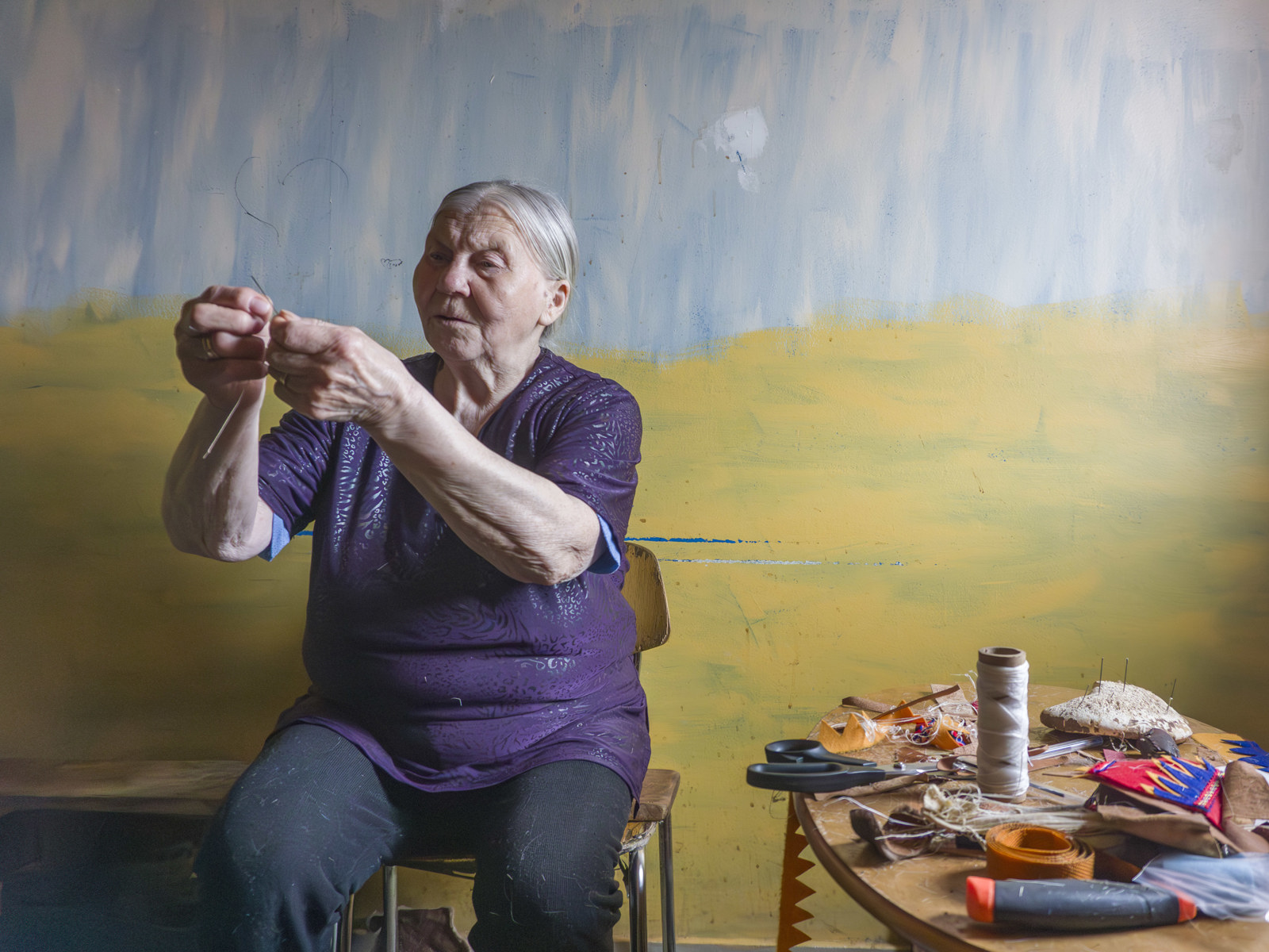 Foto av Karen Marie Somby som syr, fargerikt rom.