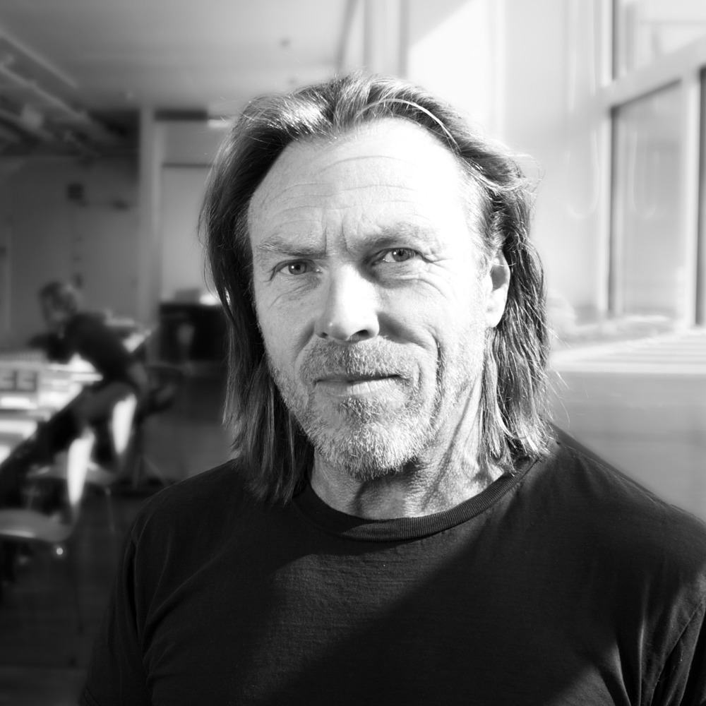 Svart hvitt foto av Herman Fuglu, kontorlandskap i bakgrunnen.