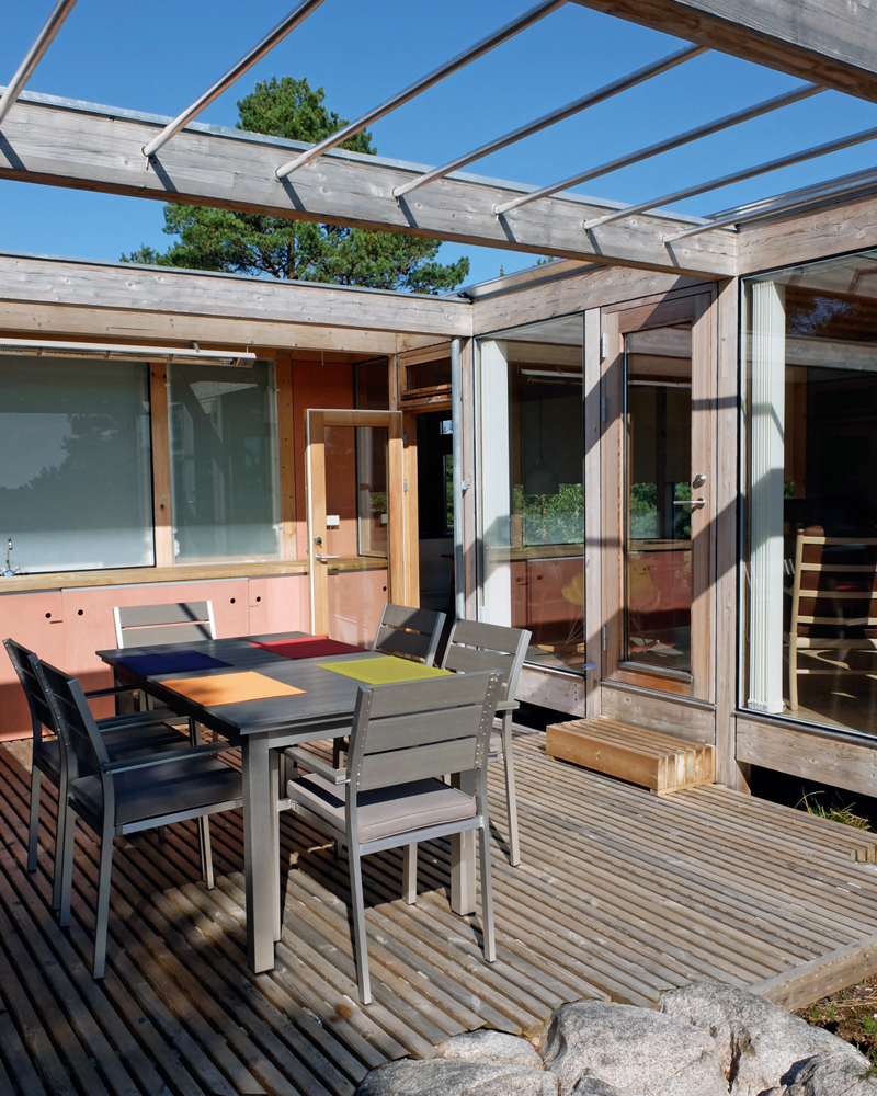 Platting utenfor hytte med pergola overbygd. Foto.