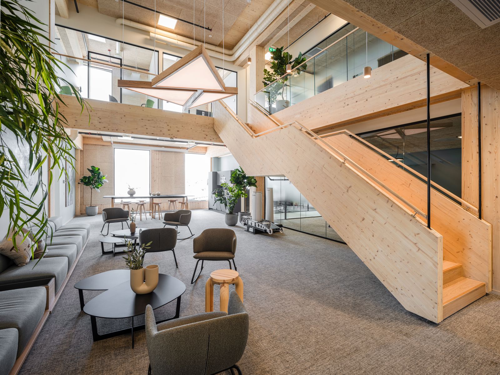 Interiørfoto av kontor/næringsbygg, dobbelthøyt fellesrom, trapper og dekker i treverk.