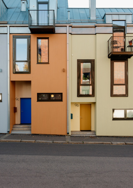 Fargerike rekkehus vender ut mot gate, en gutt går på fortauet. Foto.
